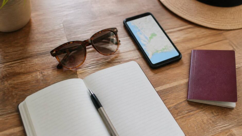 Notitieboek en reisbenodigdheden op tafel tijdens het plannen van een vakantie