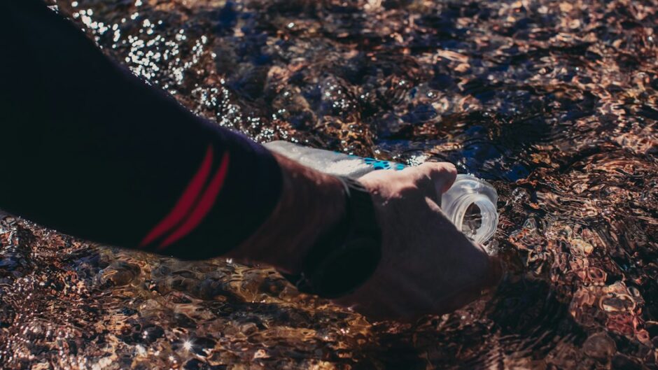 a person is holding a water bottle in the water